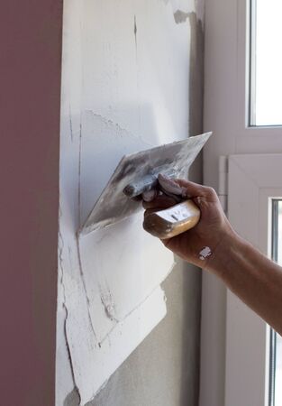 Craftsman skimming part of wall beside window.Home renovation conceptの写真素材