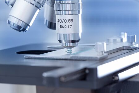 Close up of microscope lens above samples on slide glass in laboratory