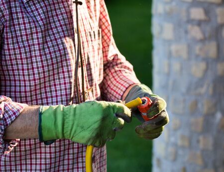 Close up of gardener mounting hose to joint and faucet for watering lawn