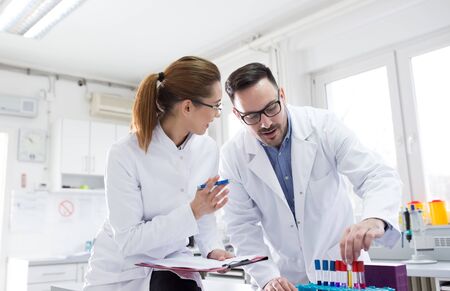 Doctor and nurse holding test tube samples and talking in laboratory