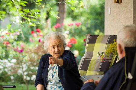 Senior man and woman talking on terrace with beautiful floral garden in background