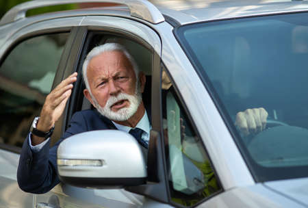 Frustraited man driving car and yelling throught window with raised arm