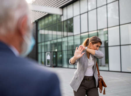 Business woman coughing and showing stop gesture to an older man with face mask who approaching to her. Virus and pandemic responsibilityの写真素材