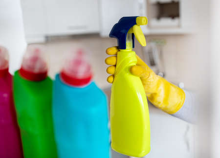 Close up of female hand with protective gloves taking spray bottle from shelfの写真素材