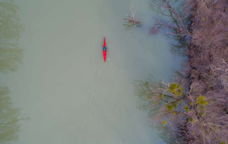 Top view of man in red kayak in cold frozen river on winter dayの写真素材