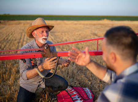 Two farmers working on tractor sprayer for plant protection, repairing equipment with wrenchの写真素材