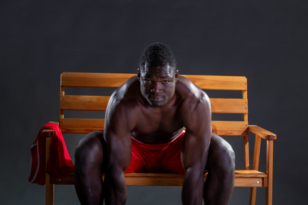 Young black sportsman sitting on a bench and looking at camera.の写真素材