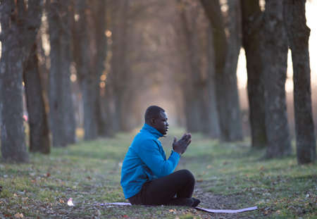 Black man sitting on exercising man in asana and meditating after workout outdoors in winter timeの写真素材