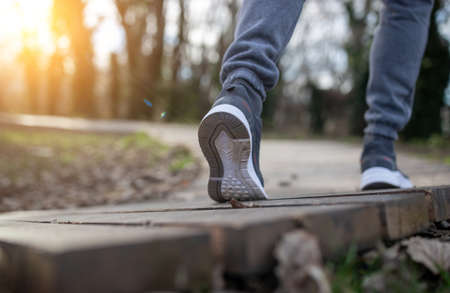 Low angle of male legs in sneakers walking or jogging on wooden trackの写真素材