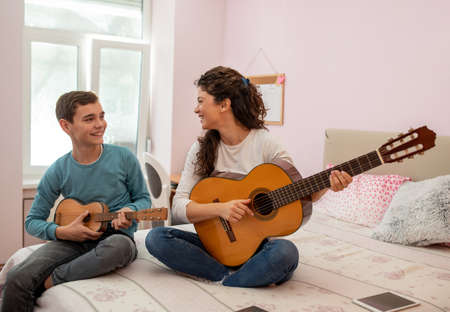 Mother and son sitting on a bed in bedroom spending quality time having fun while playing on a...