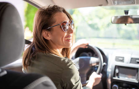 Beautiful young smiling woman driver driving a car and wearing sunglasses.の写真素材