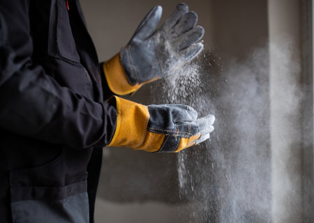 Close up of male hands with work gloves clapping to remove sawdust.