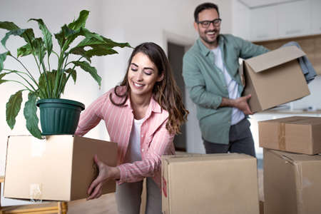 Couple moving in and brings cardboard boxes with their belongings into their new apartment.の写真素材