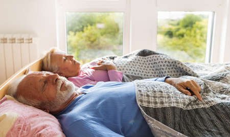 Senior coupke sleeping in bed on morning sun