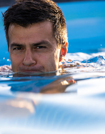 Handsome man swimming in backyard pool