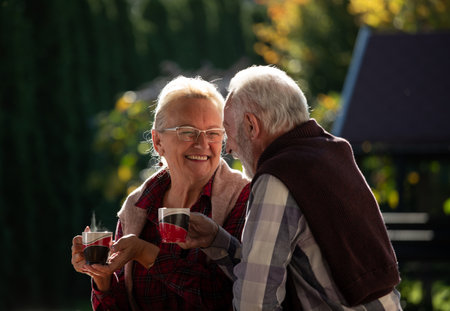 Senior couple sitting in backyard, drinking coffee and laughing