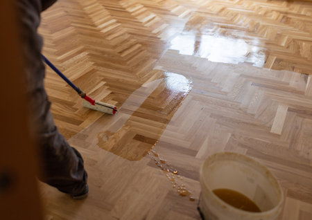 Craftsman varnishing parquet floor with lacquer by roller on stickの写真素材