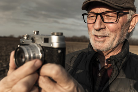 Portrait of senior man with analog camera recording field conditions in winterの写真素材