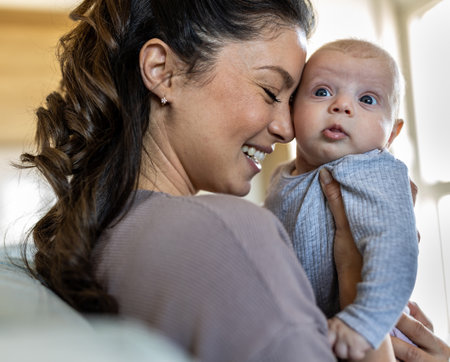 Smiling pretty mum holding infant and enjoying tender quiet moment in hug at home. Mothernity love,...