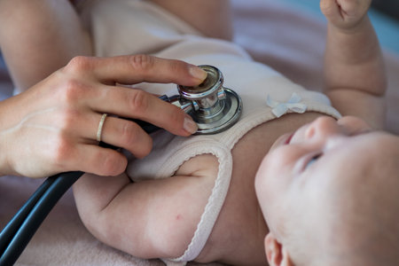 Young doctor pediatrician examining cute little baby with stethoscope in office, Close up of hand holdingの写真素材
