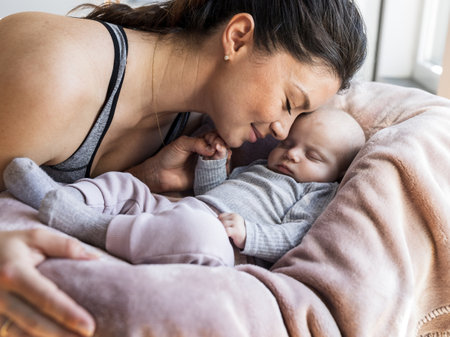 Mom cuddling with newborn baby who sleeping and holding mom's finger with small hand.  Maternity love and care conceptの写真素材
