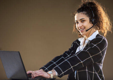 Pretty young woman with headphones and microphone smiling and working on customer service positionの写真素材