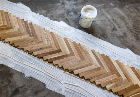 Top view of parquet boards installing in herringbone arrangement on glue, home flooring conceptの写真素材