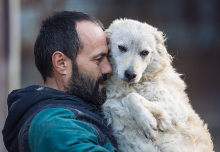Lovely moment when mature man holding and hugging cute abandoned dog in shelter. Love, care and tendernessの写真素材