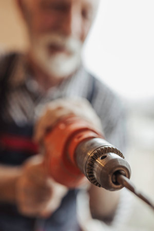 Close up of a drill. Senior craftsman repairing something at homeの写真素材