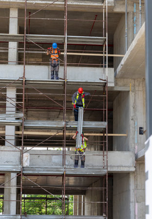 Construction workers assembling scaffolding on a construction site in an urban area during daylight...