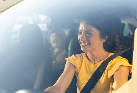 Beautiful young mother smiling as she drives her little daughter to school in a modern car