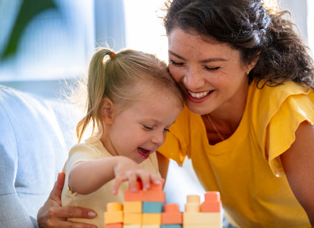 Mother and child enjoy joyful afternoon playing with colorful building blocks in sunlit room,...