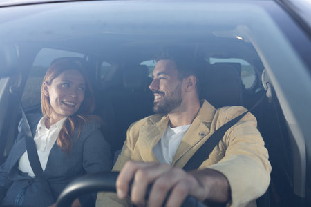 Man and woman in formal attire looking at each other and smiling while sitting in a modern car....