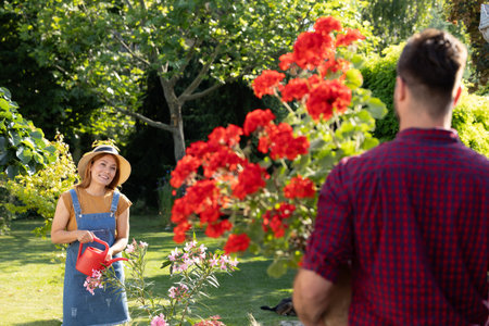 Woman tends to colorful flowers in a sunny garden, enjoying the lush greenery and warm weather. A...
