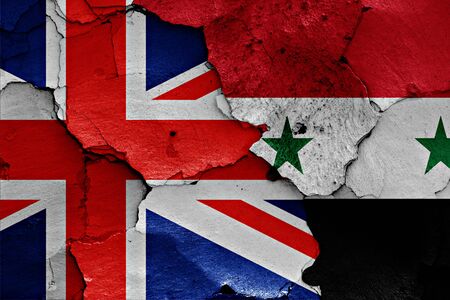 flags of UK and Syria painted on cracked wallの写真素材