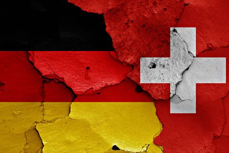 flags of Germany and Switzerland painted on cracked wallの写真素材