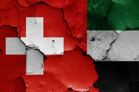 flags of Switzerland and United Arab Emirates painted on cracked wallの写真素材
