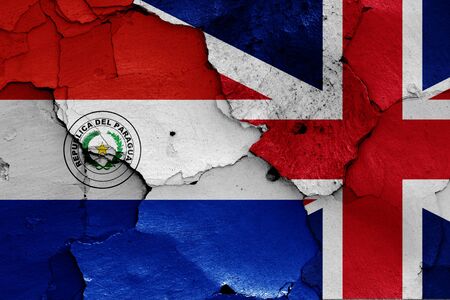 flags of Paraguay and UK painted on cracked wallの写真素材