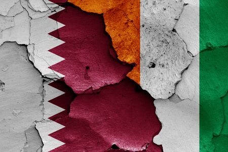flags of Qatar and Ivory Coast painted on cracked wallの写真素材