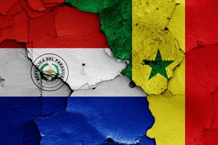 flags of Paraguay and Senegal painted on cracked wallの写真素材