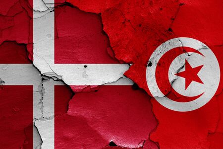 flags of Denmark and Tunisia painted on cracked wallの写真素材