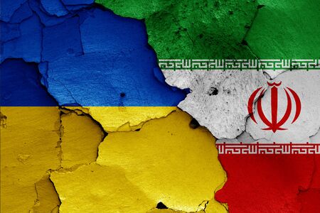 flags of Ukraine and Iran painted on cracked wallの写真素材