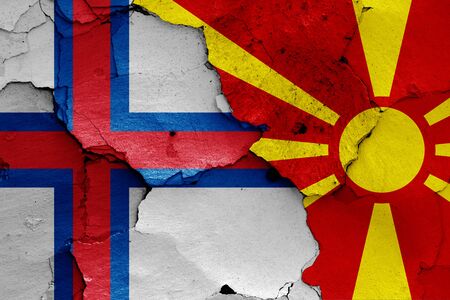 flags of Faroe Islands and North Macedonia painted on cracked wallの写真素材