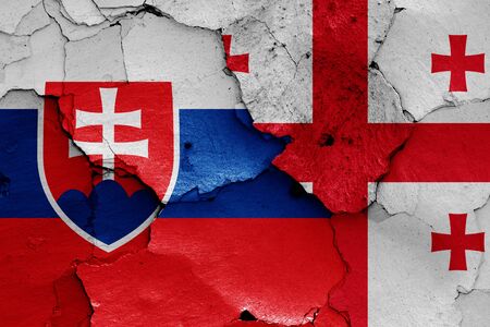 flags of Slovakia and Georgia painted on cracked wallの写真素材