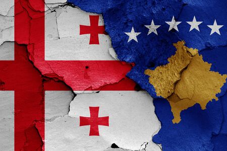 flags of Georgia and Kosovo painted on cracked wallの写真素材