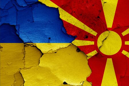flags of Ukraine and North Macedonia painted on cracked wallの写真素材