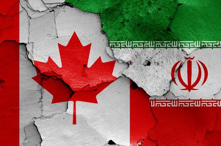 flags of Canada and Iran painted on cracked wallの写真素材