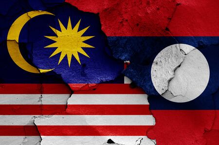 flags of Malaysia and Laos painted on cracked wallの写真素材