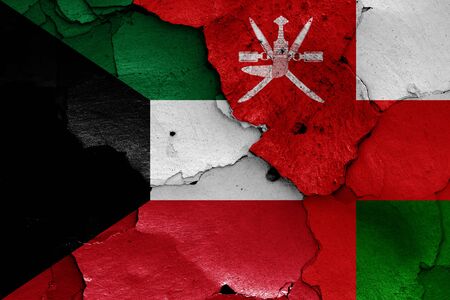 flags of Kuwait and Oman painted on cracked wallの写真素材