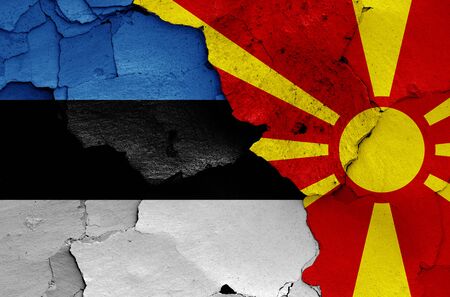 flags of Estonia and North Macedonia painted on cracked wallの写真素材